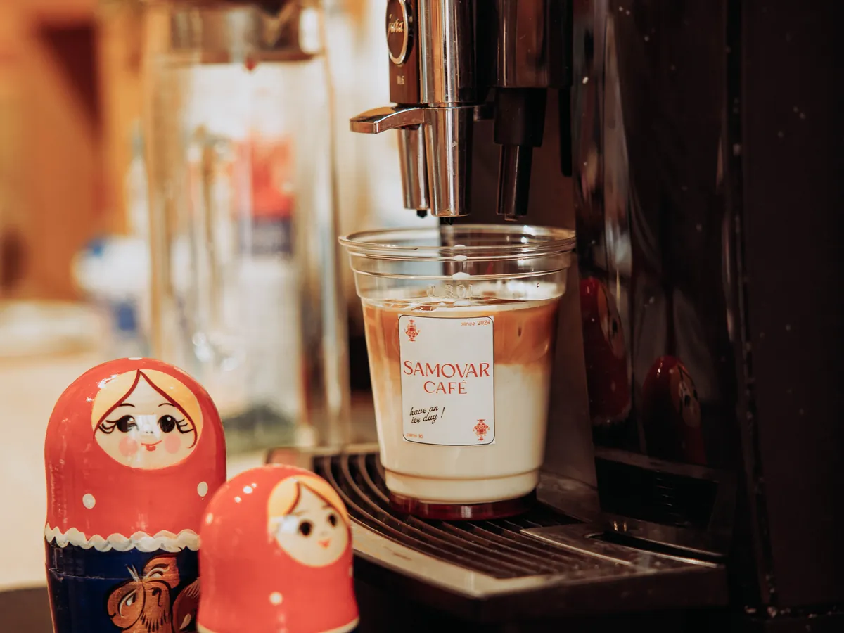 Un latte glacé du Samovar Café sous la machine à espresso, à côté de deux matriochkas.