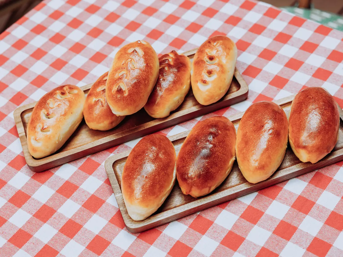 Deux plateaux de pirojki dorés sur une nappe vichy rouge et blanc.