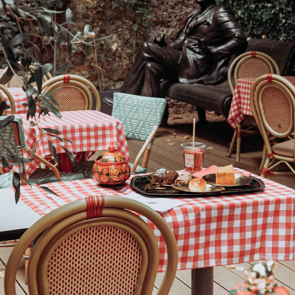 La statue de Rachmaninoff dans la cour, derrière une table vichy dressée avec un plateau de douceurs et un sucrier peint.